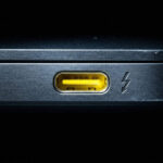 Qual é a verdadeira função da porta USB amarela e qual é a sua principal desvantagem?