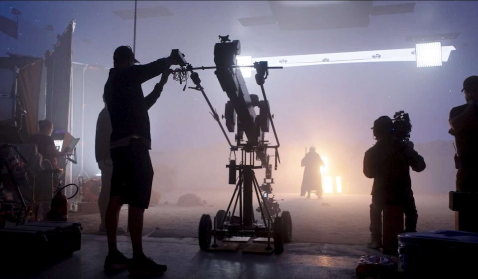 Técnico ajusta equipamento de câmera em estúdio de filmagem envolto em névoa